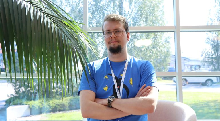 Puolikuva toimistoinsinööriharjoittelija Hugosta. Vasemmalla viherkasvi.